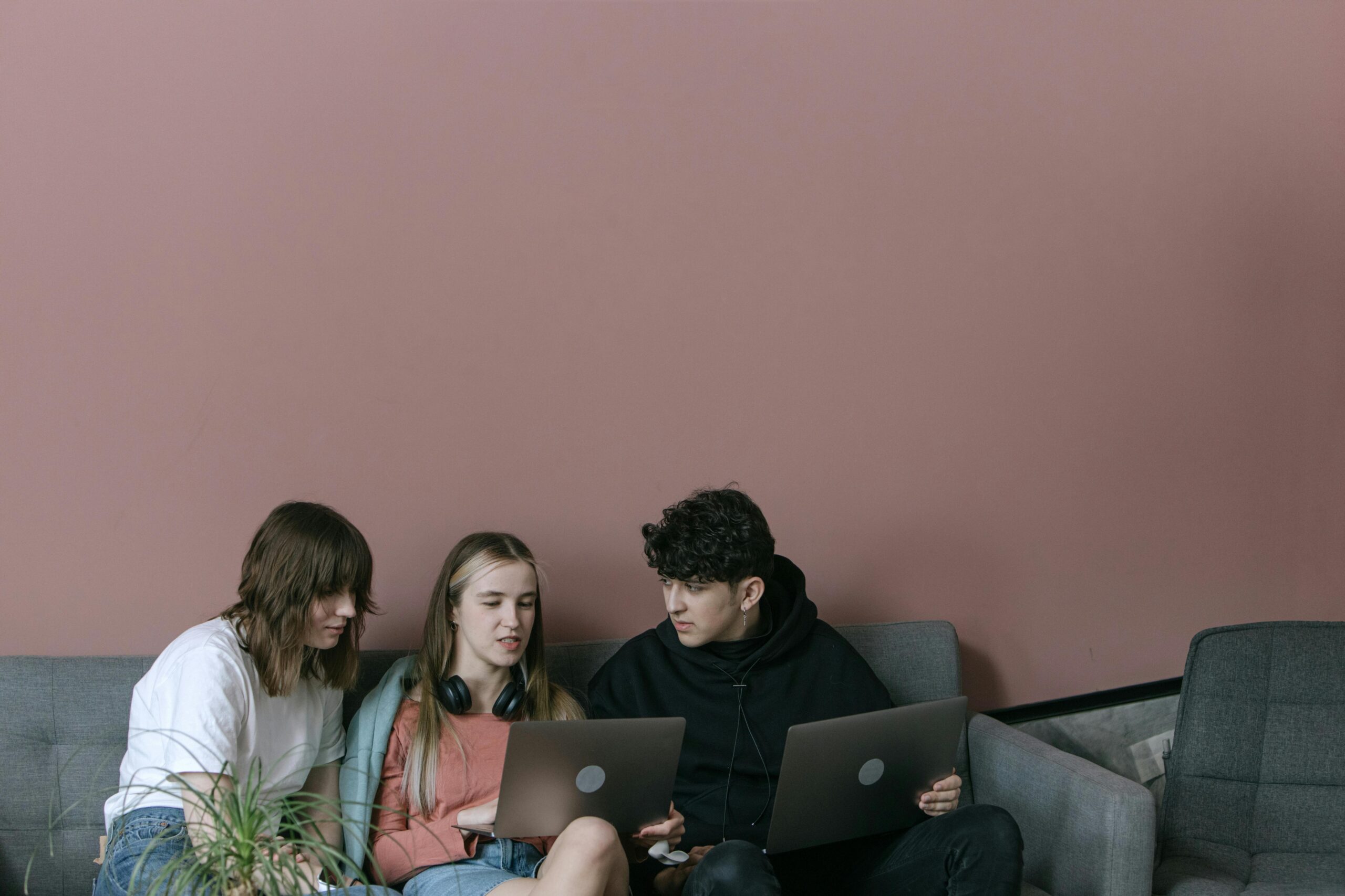 Three young adults collaborating with laptops in a cozy indoor setting.